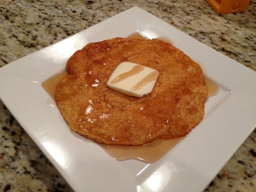 Buttery pancake with syrup on plate.