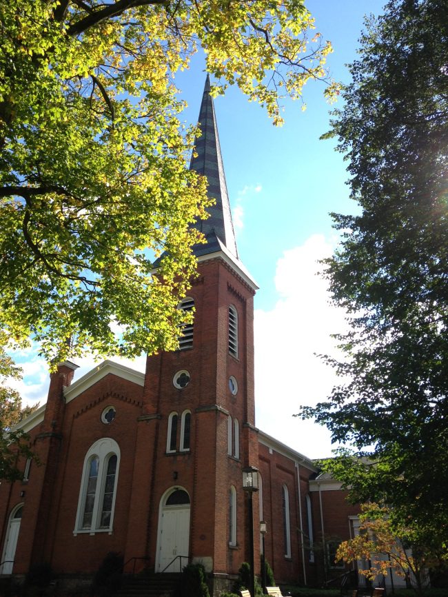 Brick church steeple, autumn leaves.