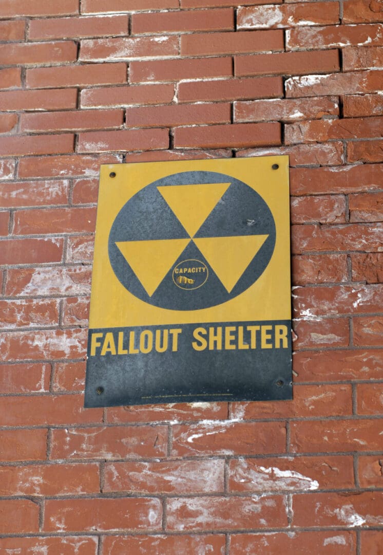 Fallout shelter sign on brick wall.