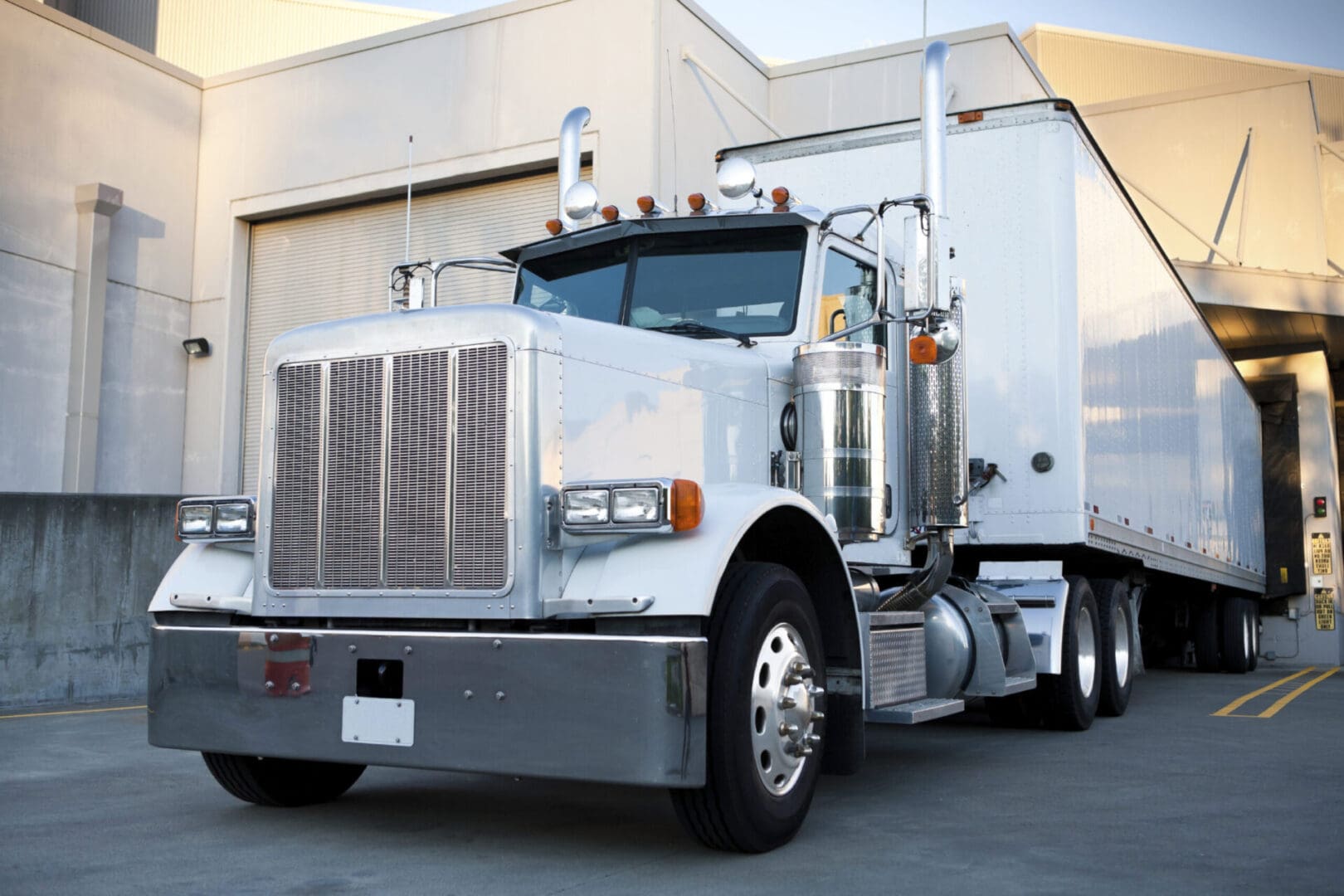 Silver semi-truck parked at loading dock.