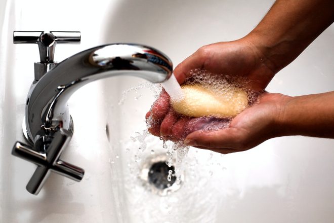 Hands washing soap under running water.
