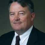 Here's an alt tag for the image: Headshot of a man in a suit.