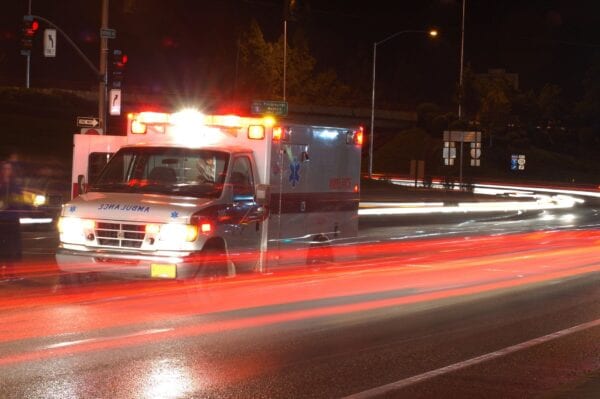 A ambulance is driving down the street at night.