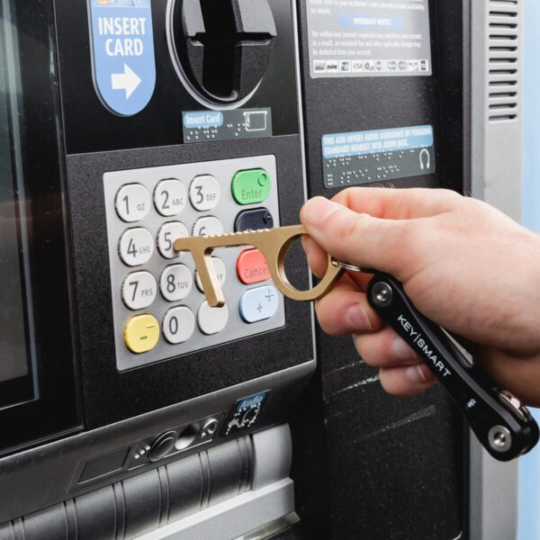 A person holding a wrench near the atm machine.