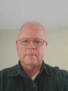 Portrait of an older man wearing glasses and a dark shirt.