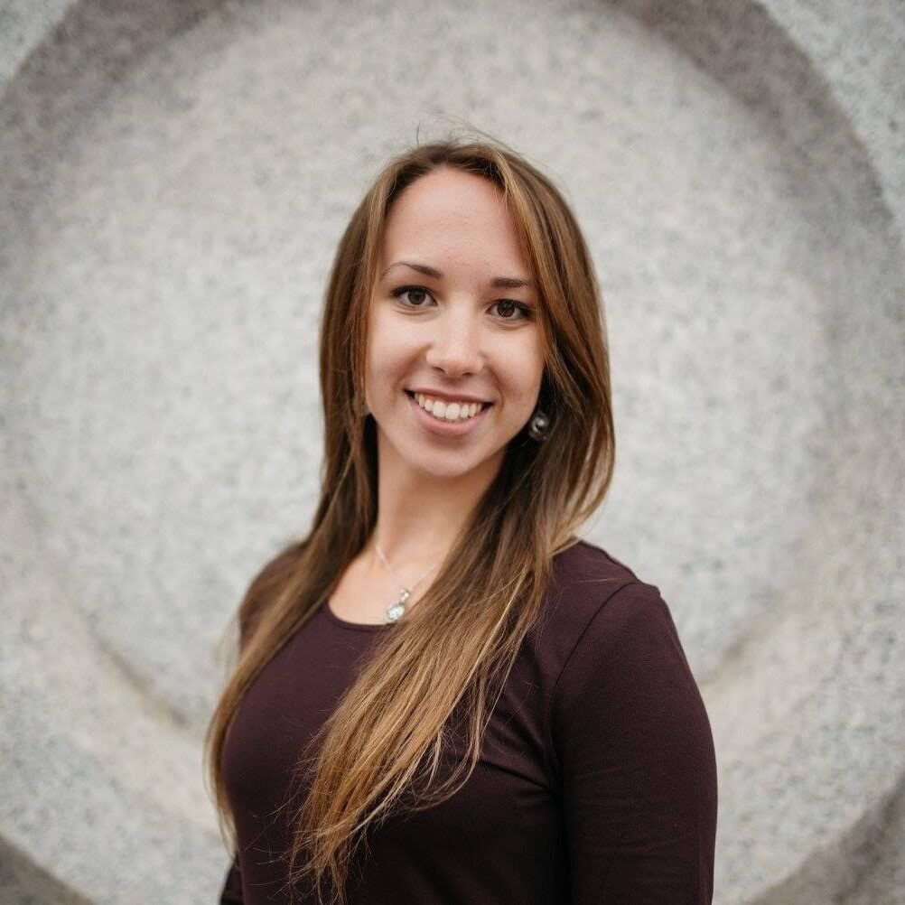 A woman standing in front of an abstract background.