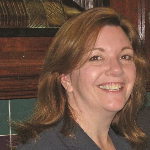 A woman with long hair smiles for the camera.