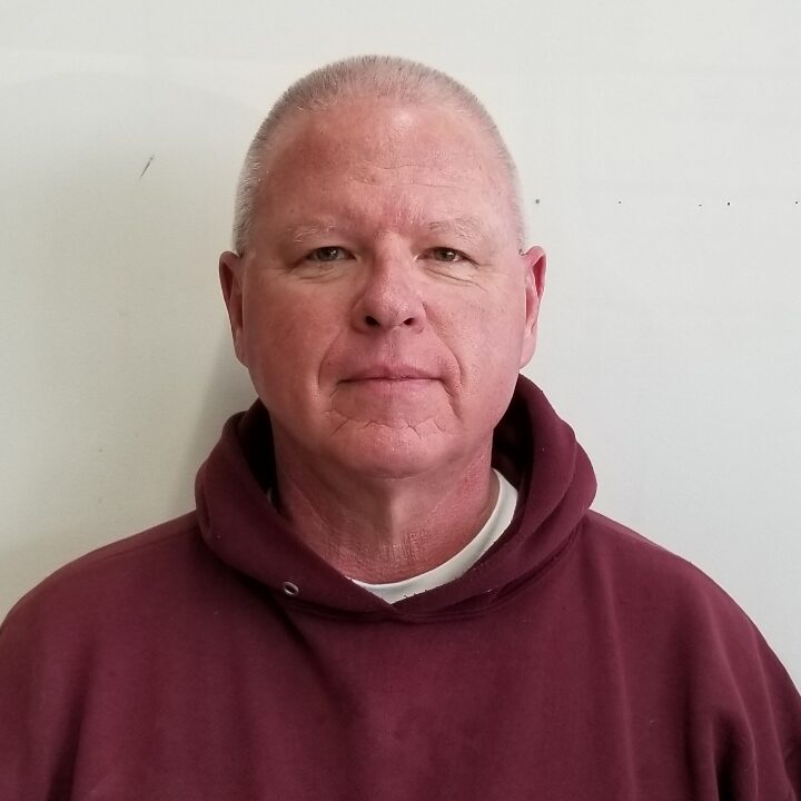 A man in a hooded sweatshirt is posing for the camera.