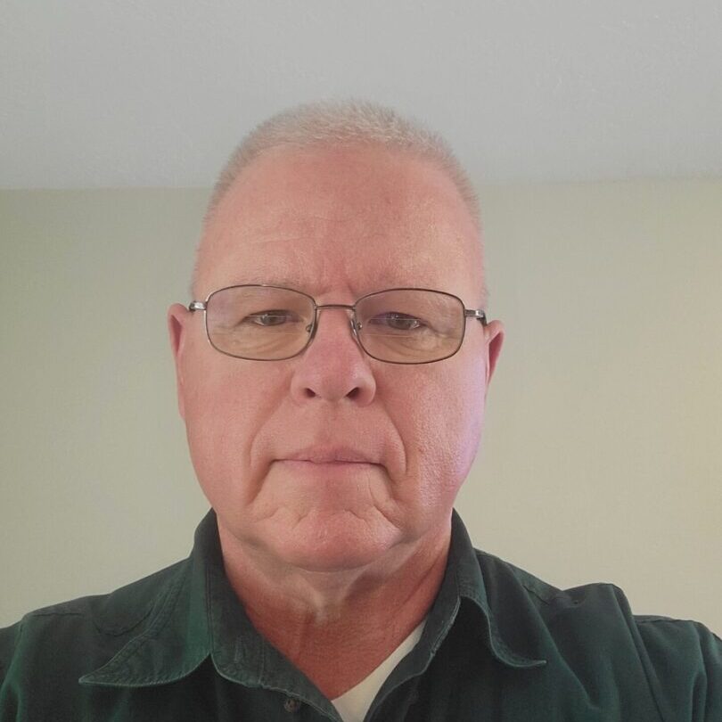 Portrait of an older man wearing glasses and a dark shirt. Portrait of an older man wearing glasses and a dark shirt.